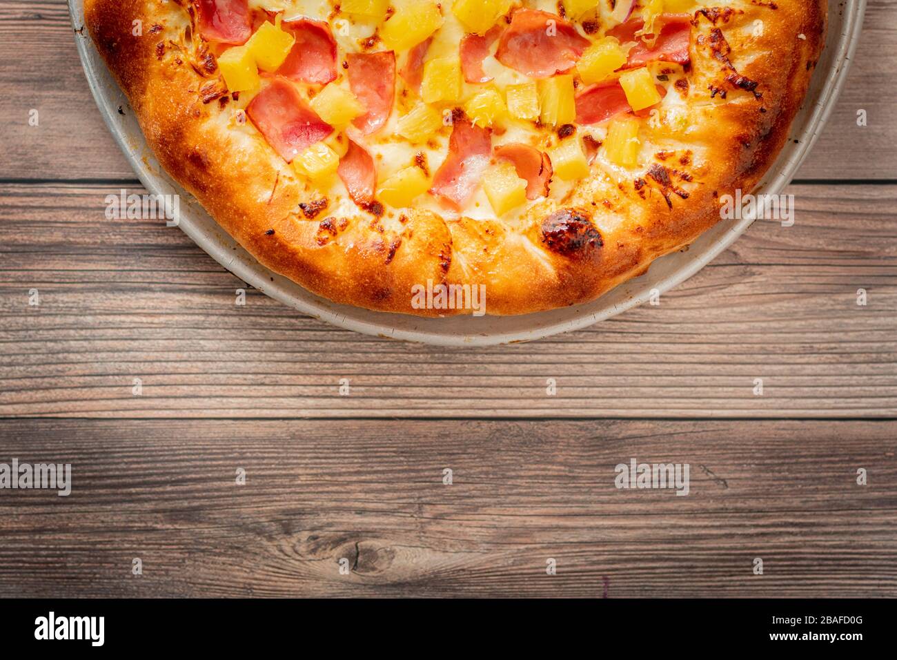 High-Angle-Schuss einer frisch gebackenen Pizza mit Ananas auf Eine hölzerne Oberfläche Stockfoto