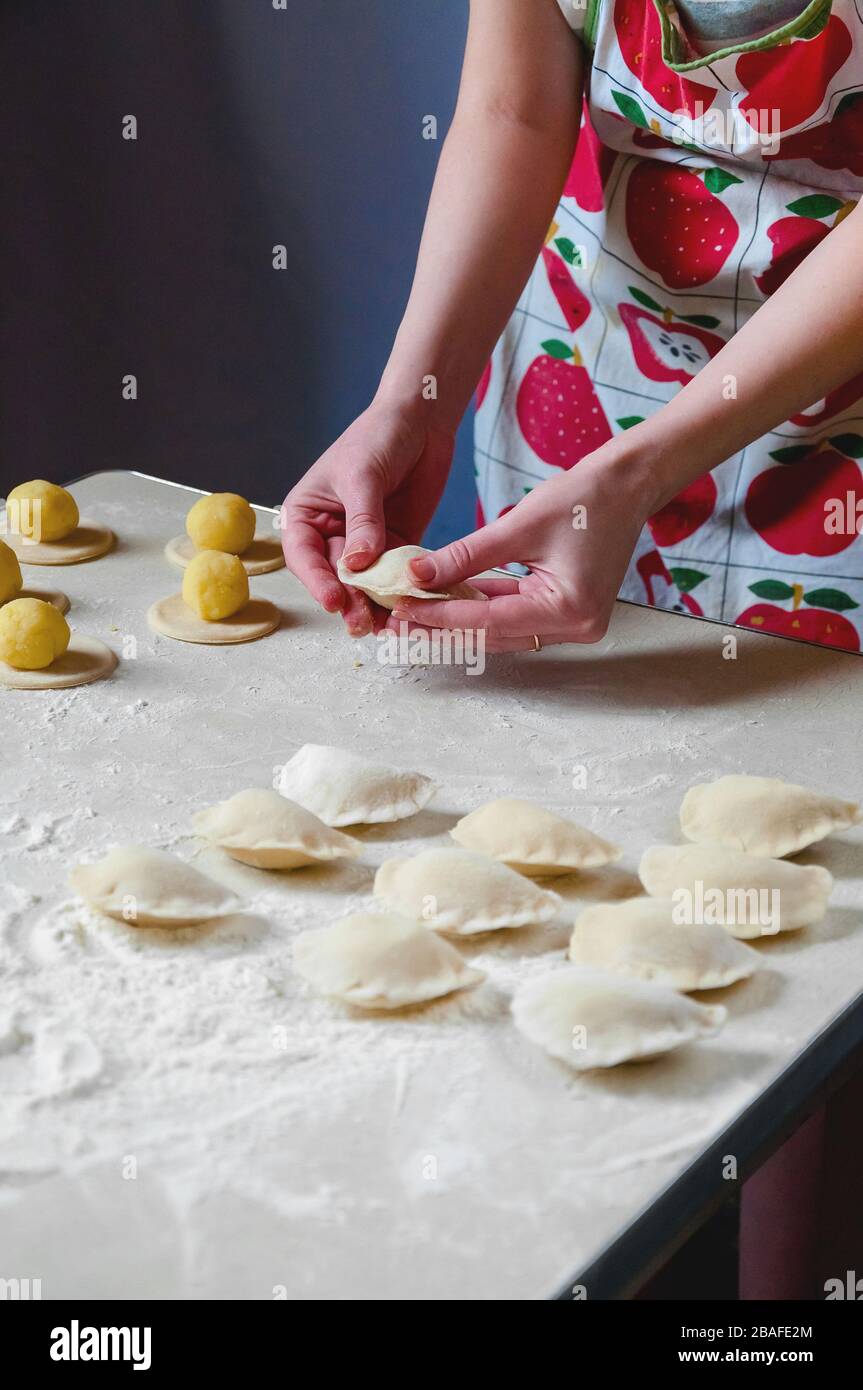 Frau übergibt auf weißem Hintergrund Knödel mit Kartoffeln. Traditionelle Ukrainische Küche. Stockfoto