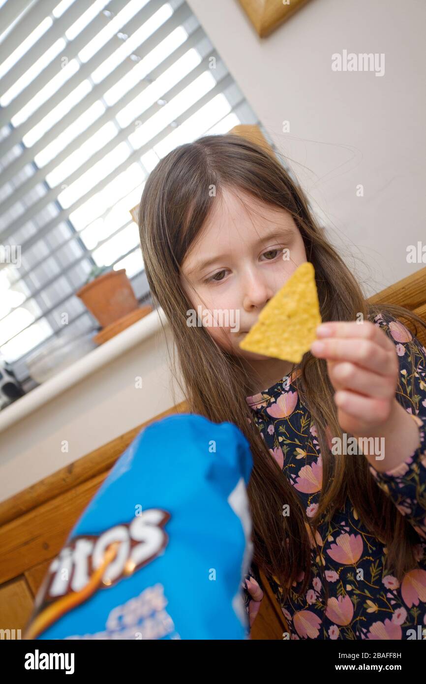 Junges Mädchen, das einen coolen Dorito Chip ansieht Stockfoto