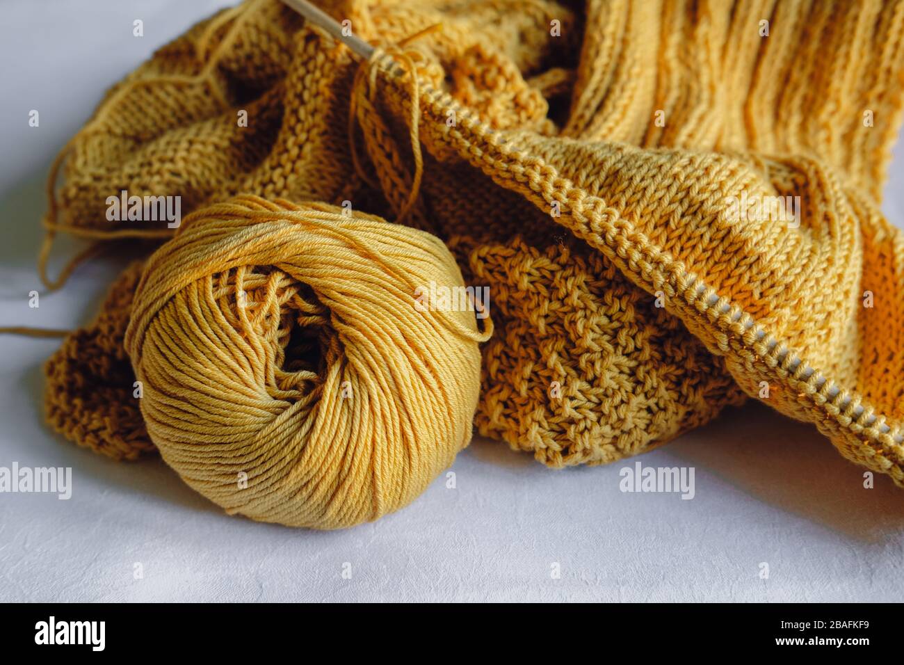 Gelbe Strickgarnkugel mit Nadeln Stockfoto