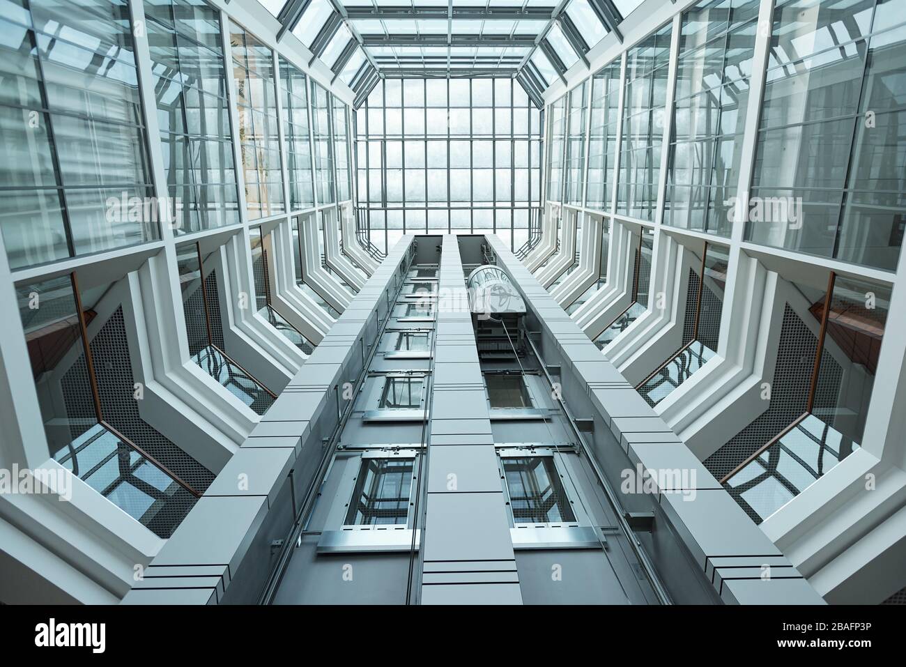 Blick unter die Gestaltung des modernen Innenraums des Business Centers, umgeben von Wänden und Fenstern und beweglicher Aufzugsvorrichtung Stockfoto