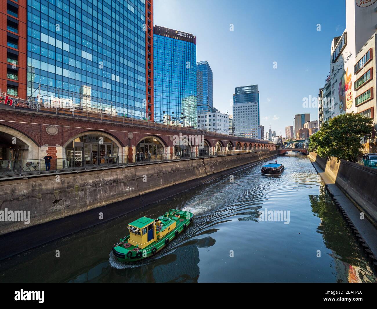 Flussverkehr auf dem Fluss Tokio-Kanda, während er durch den Stadtteil Akihabara führt. Ein Schlepper und ein Schleppkahn auf dem Kanda-Fluss in Tokyo Japan. Stockfoto