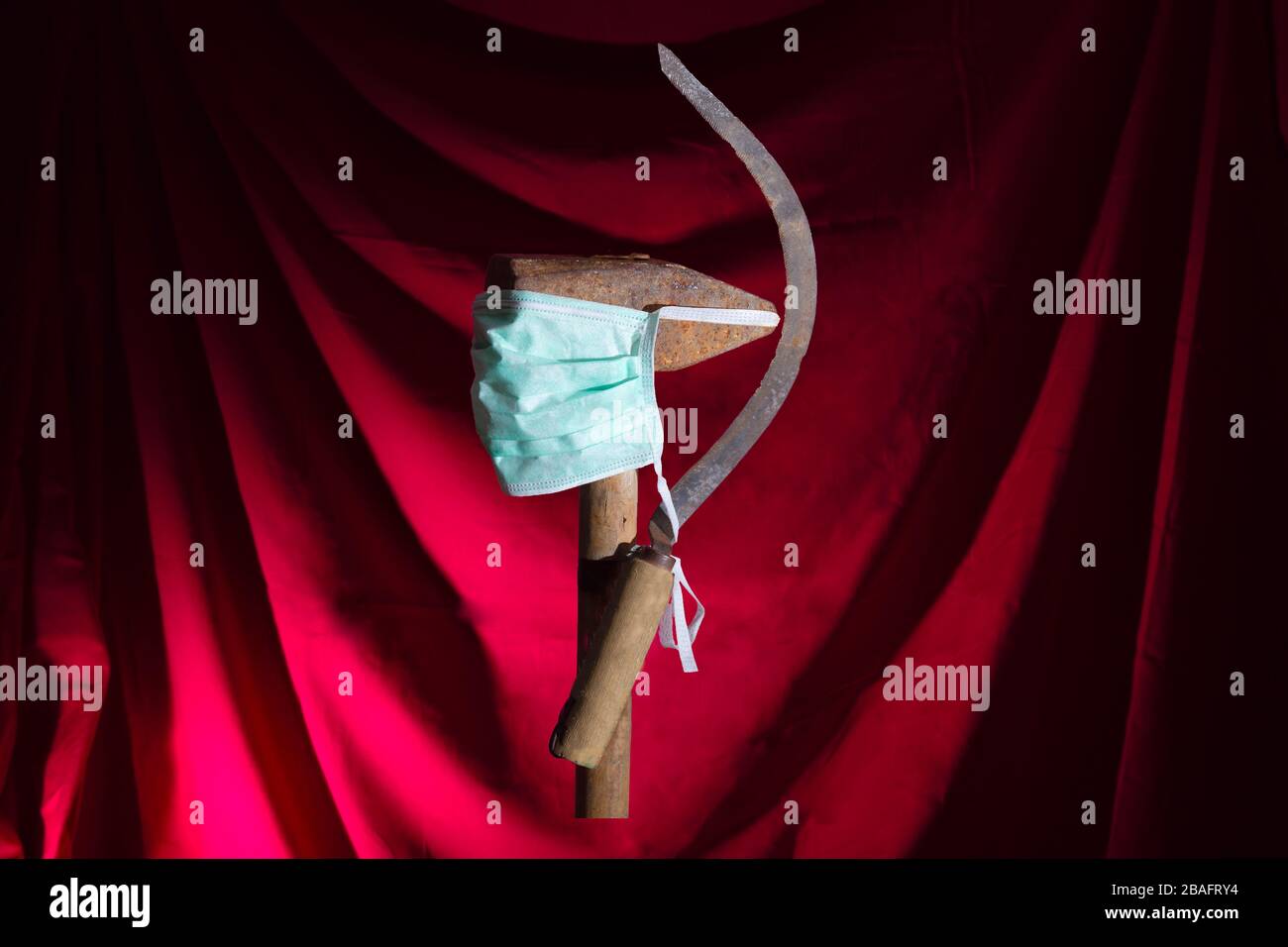 Eine Sichel und einen Hammer in einer medizinischen Maske. Symbol des Weltpretariats, kommunistisches Wappen in Zeiten der Pandemie, Epidemie. Stockfoto