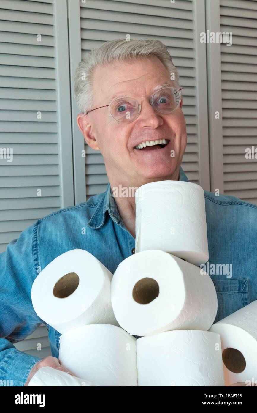Leitender Mann, der während der Pandemie von Coronavirus, USA, zusätzliche Rollen Toilettenpapier hält Stockfoto