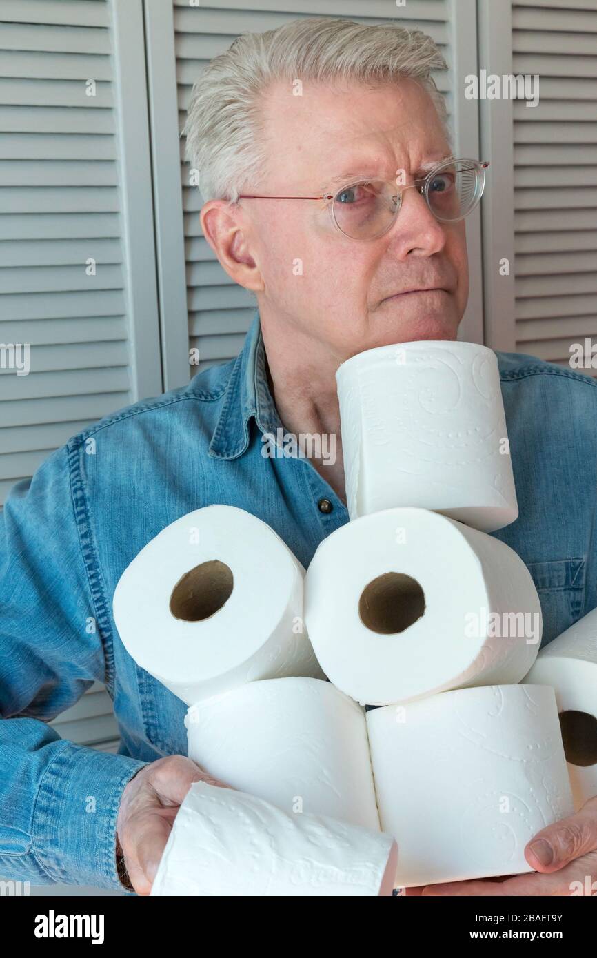 Leitender Mann, der während der Pandemie von Coronavirus, USA, zusätzliche Rollen Toilettenpapier hält Stockfoto