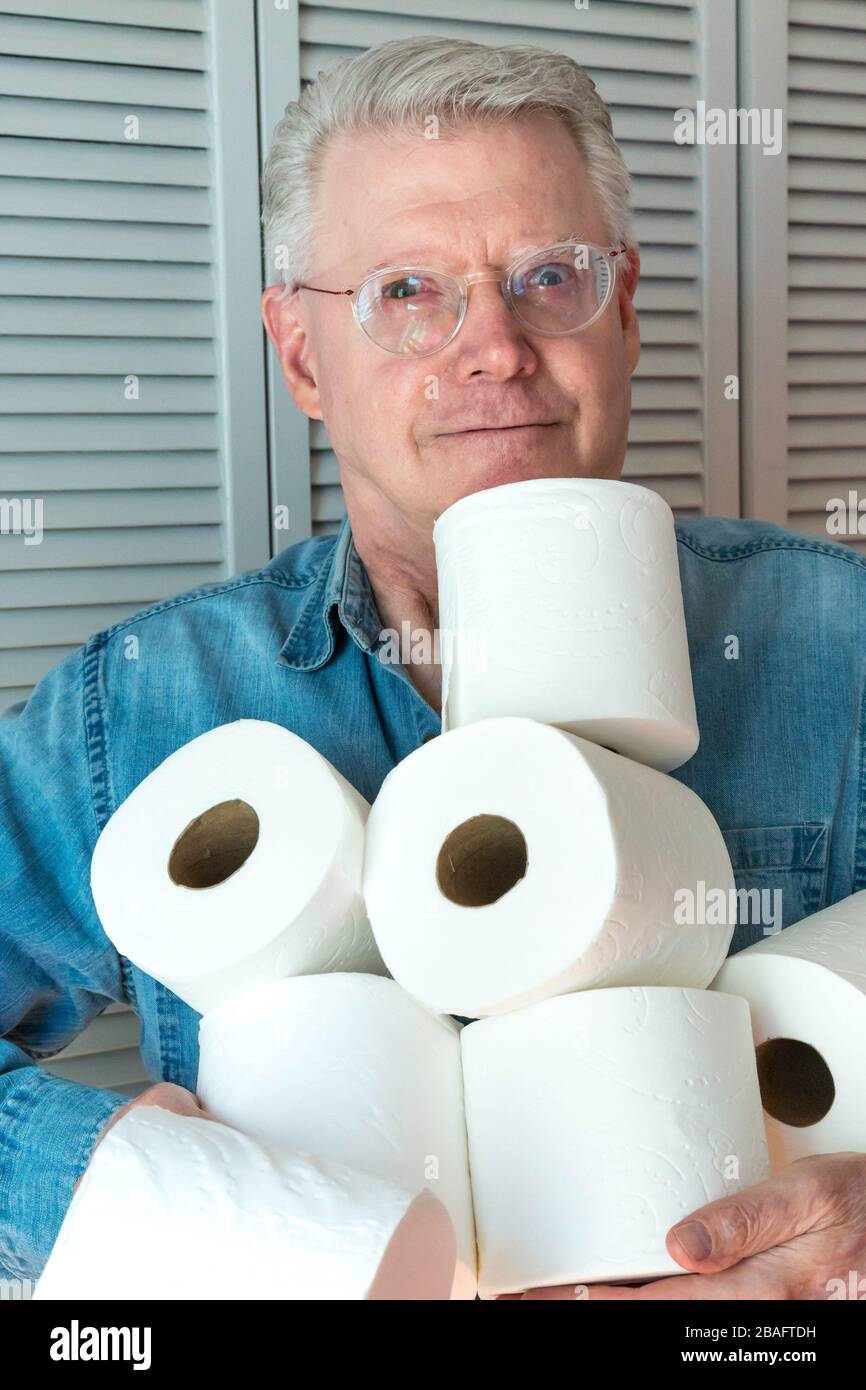 Leitender Mann, der während der Pandemie von Coronavirus, USA, zusätzliche Rollen Toilettenpapier hält Stockfoto