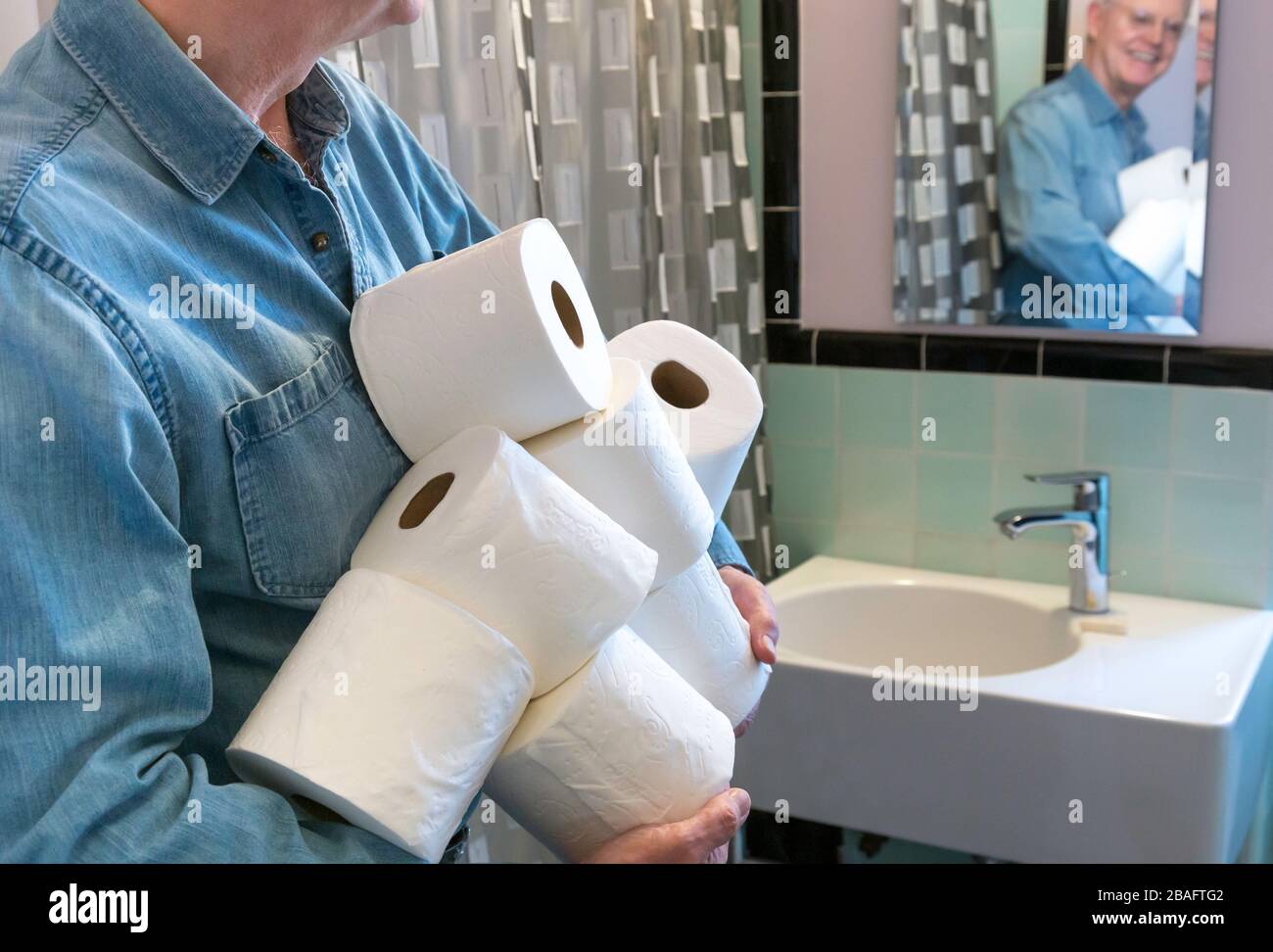 Leitender Mann, der während der Pandemie von Coronavirus, USA, zusätzliche Rollen Toilettenpapier hält Stockfoto