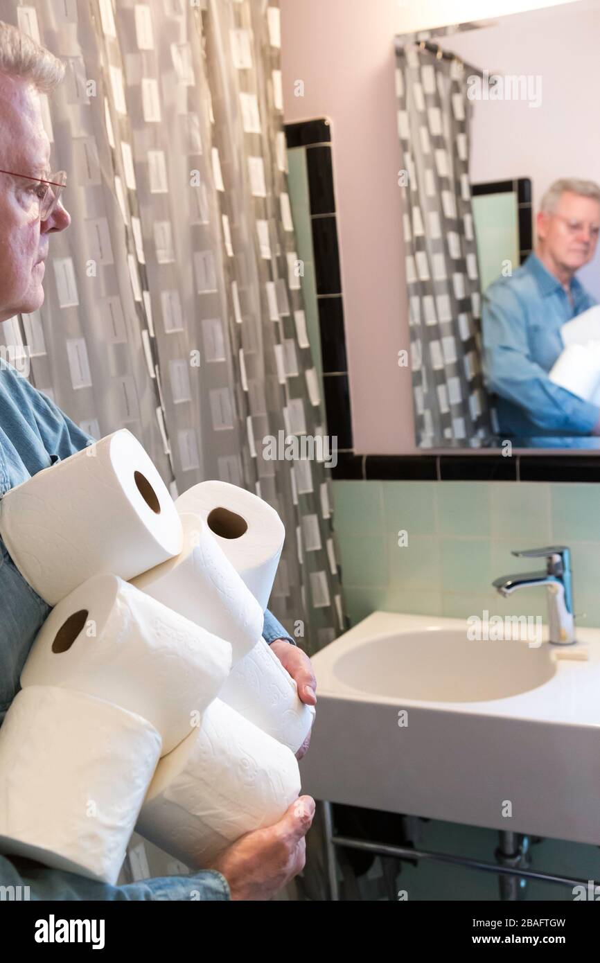 Leitender Mann, der während der Pandemie von Coronavirus, USA, zusätzliche Rollen Toilettenpapier hält Stockfoto