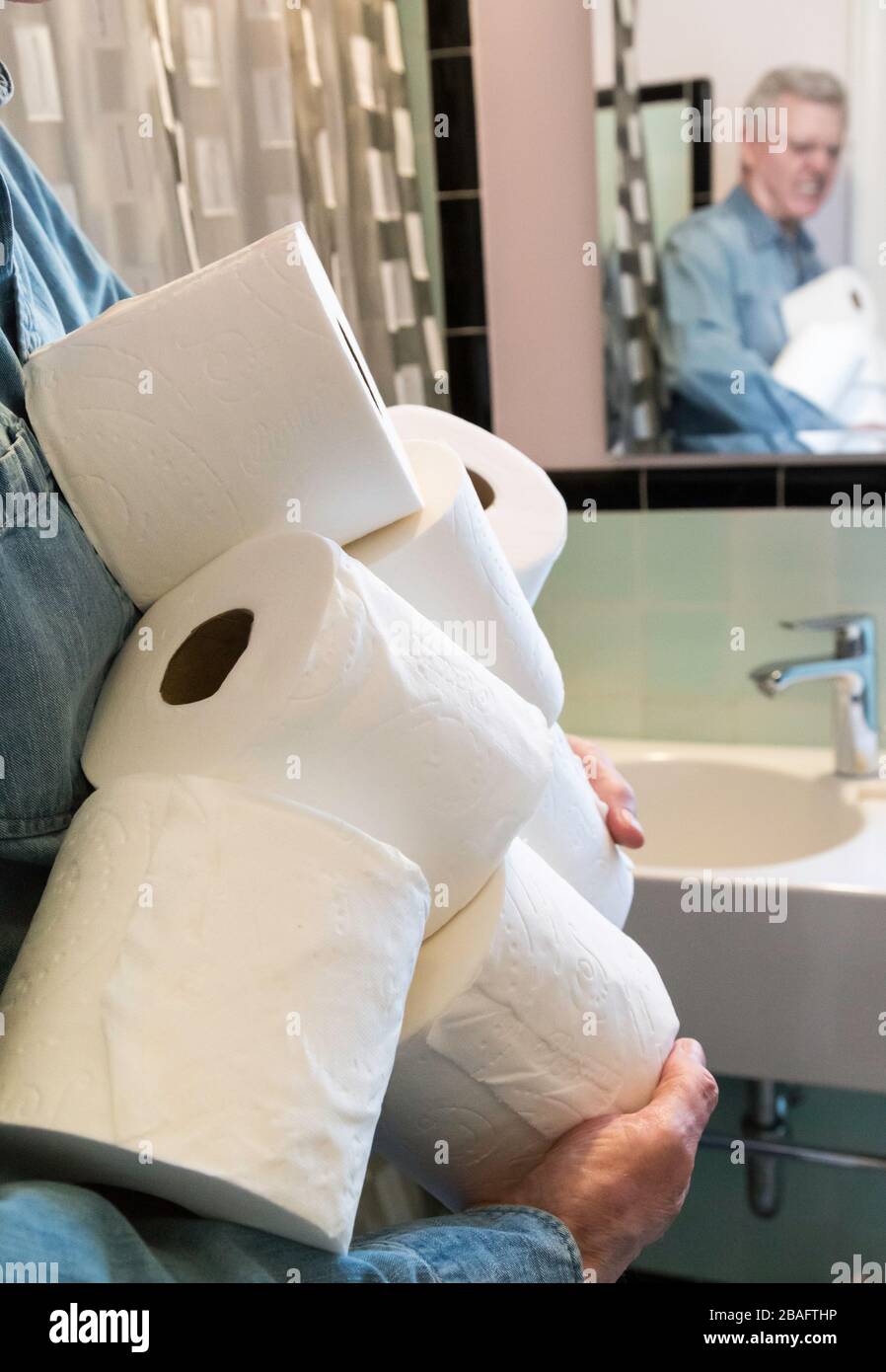 Senior man hält zusätzliche Rollen Toilettenpapier während der Coronavirus-Pandemie, USA 2020 Stockfoto