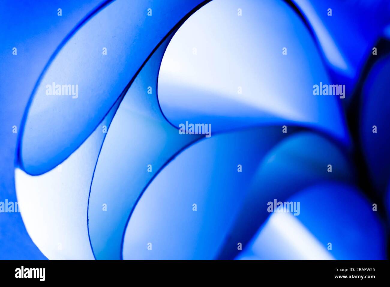 Abstraktes blaues Papier, das sich mit Licht durch die Kurven entwirbelt Stockfoto