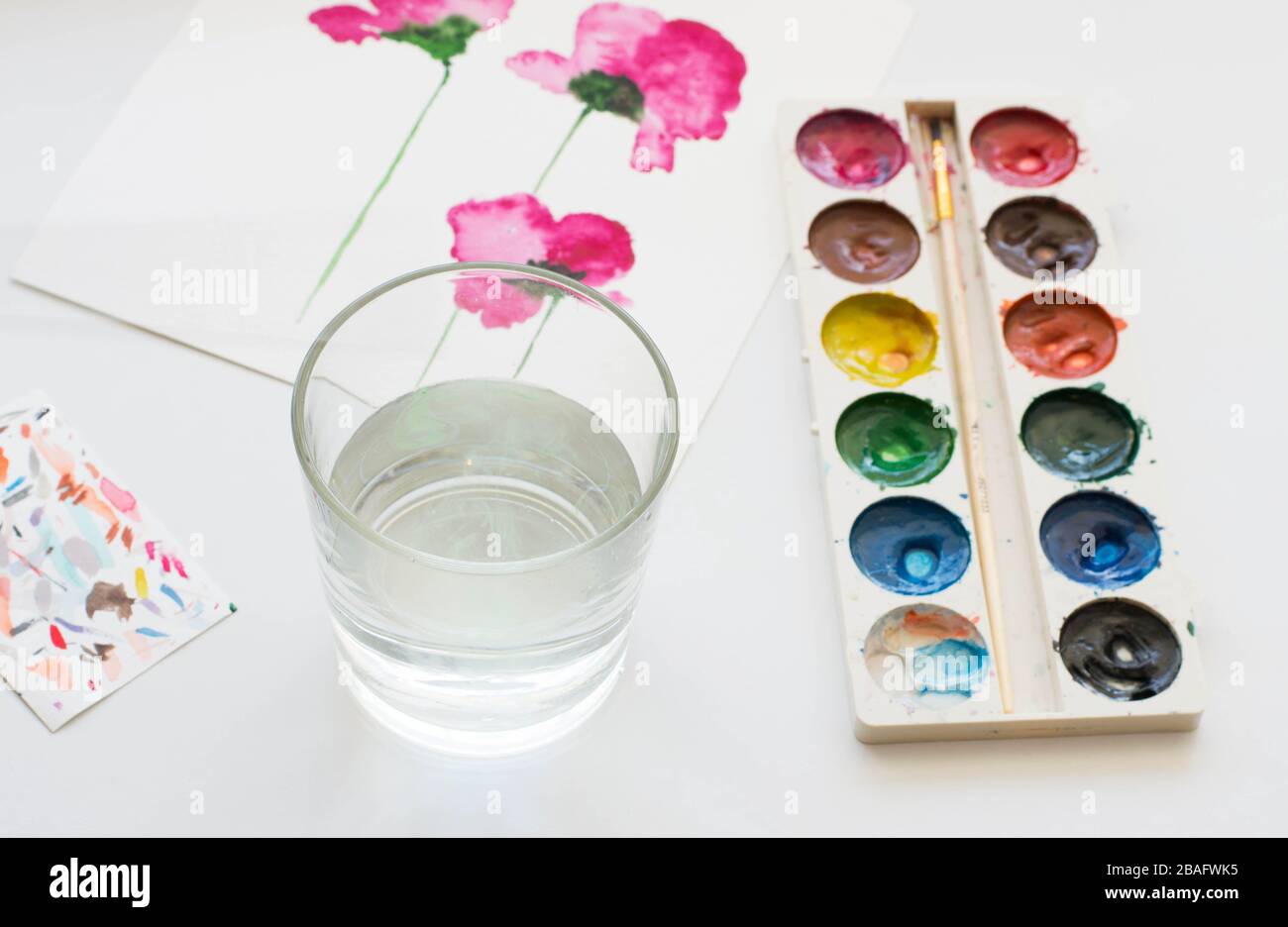 Aquarellgemälde mit rosafarbenen magnolienblüten und künstlerischen Werkzeugen auf weißem Tisch. Stillleben Komposition von künstlerischen Arbeitsplätzen Stockfoto