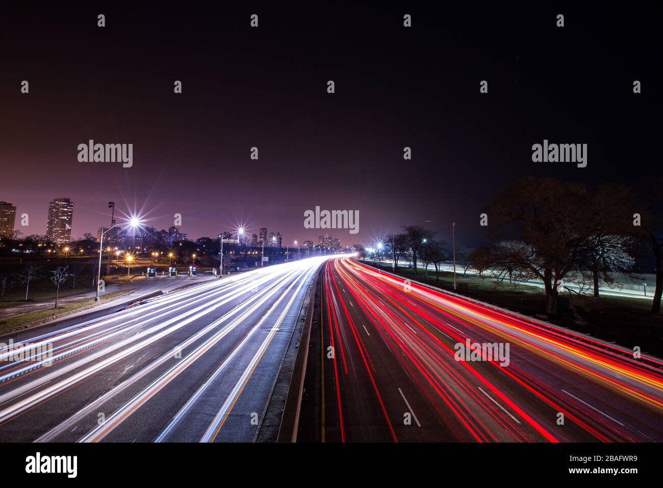 Lange Belichtung von weißen und roten Lichtstrahlen von Verkehrswagen, während sie sich entlang der Stadtstraße bewegen Stockfoto