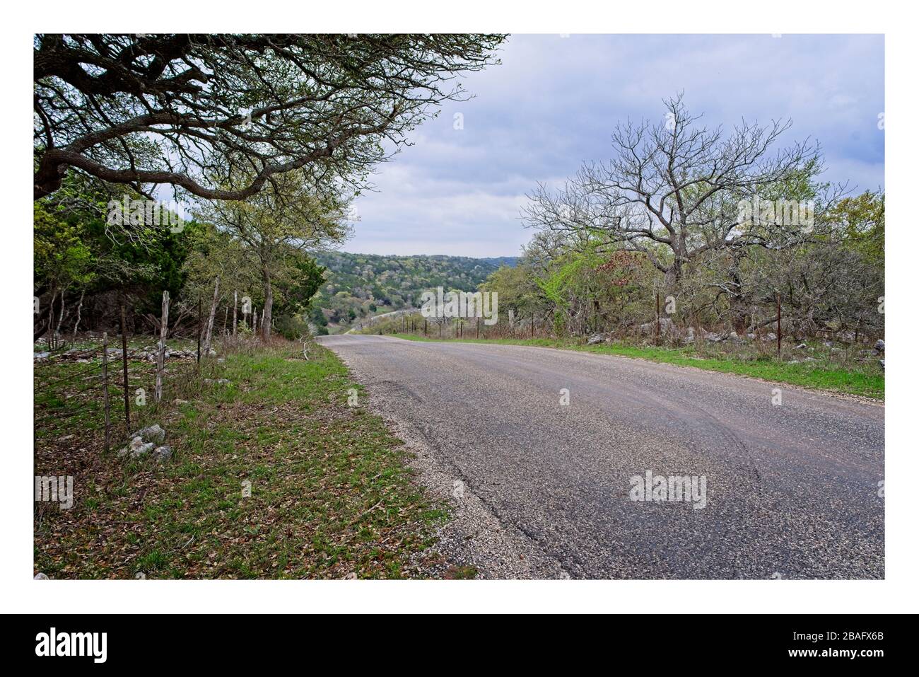 Texas Hill Country Landstraße mit Hügeln und bewölktem Himmel Stockfoto