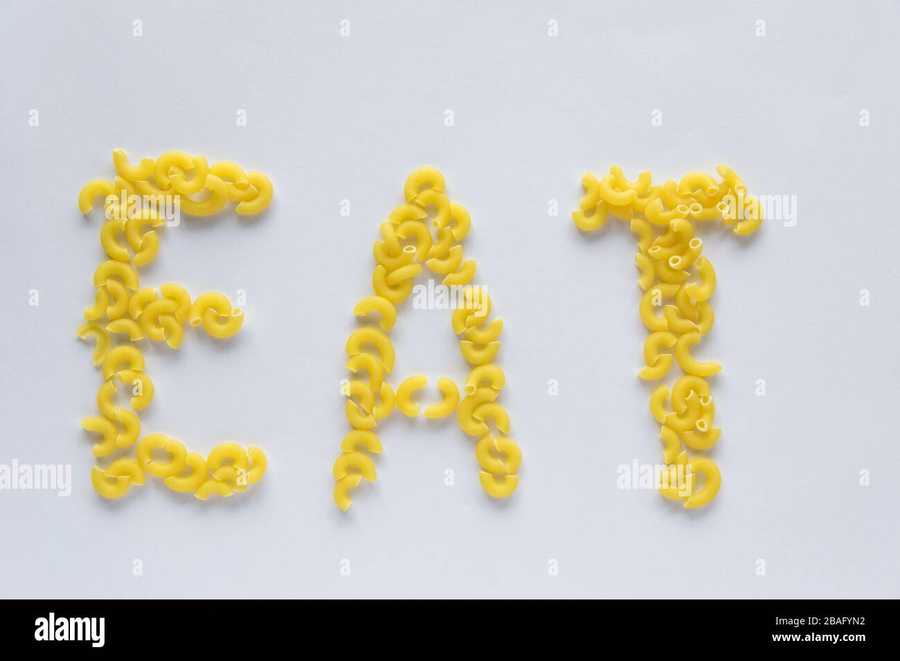 Wortessen. Italienisches Lebensmittelkonzept und Menüdesign. Ungekochte Pasta auf weißem Hintergrund. Flaches Lay. Draufsicht. Stockfoto