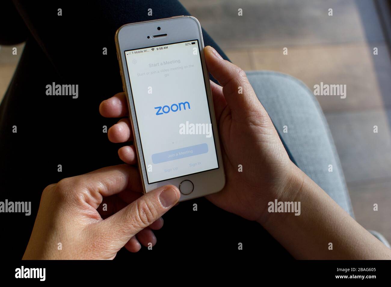 Eine Frau, die die Mobile-App "Zoom" auf ihrem Telefon öffnet. Zoom-Benutzer können Sitzungen aufzeichnen, an Projekten zusammenarbeiten und Anmerkungen auf den Bildschirmen der anderen Benutzer erstellen. Stockfoto
