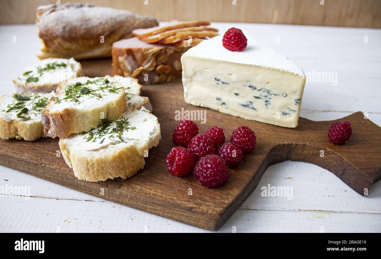 Sandwiches auf einem Holzbrett. Auf weißem Hintergrund. Käse, Schinken und Himbeeren. Snack. Copyspace Stockfoto