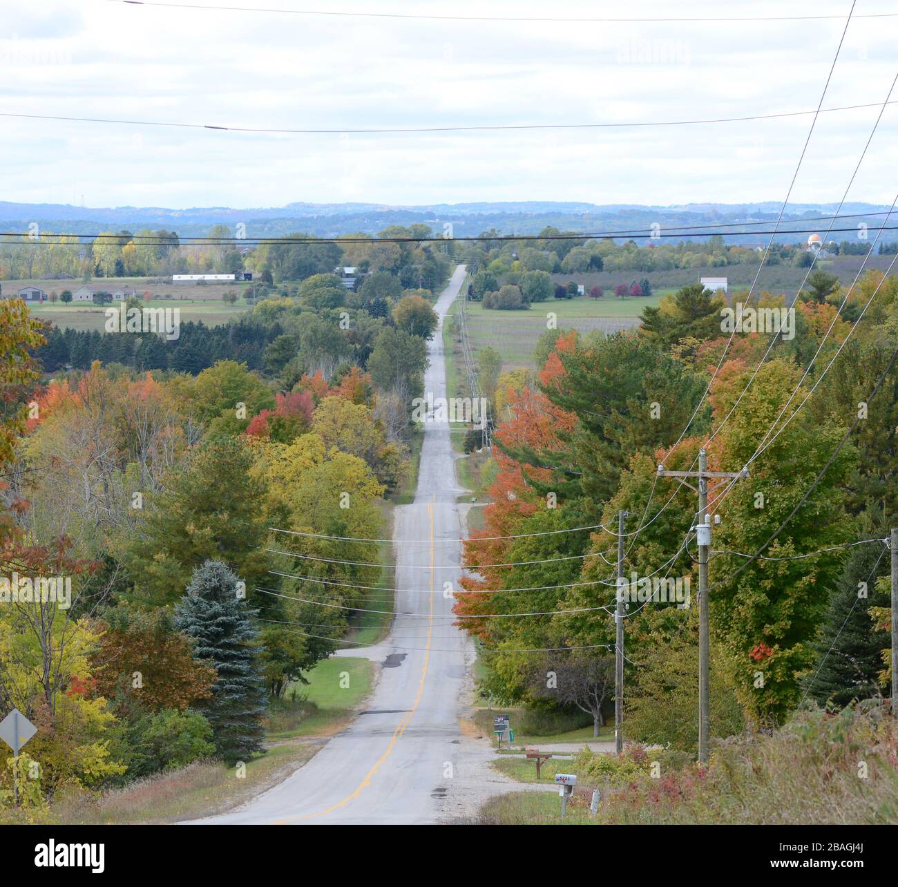 Eine Hügellandstraße erstreckt sich bis in die Ferne. Herbstlaub. Stockfoto