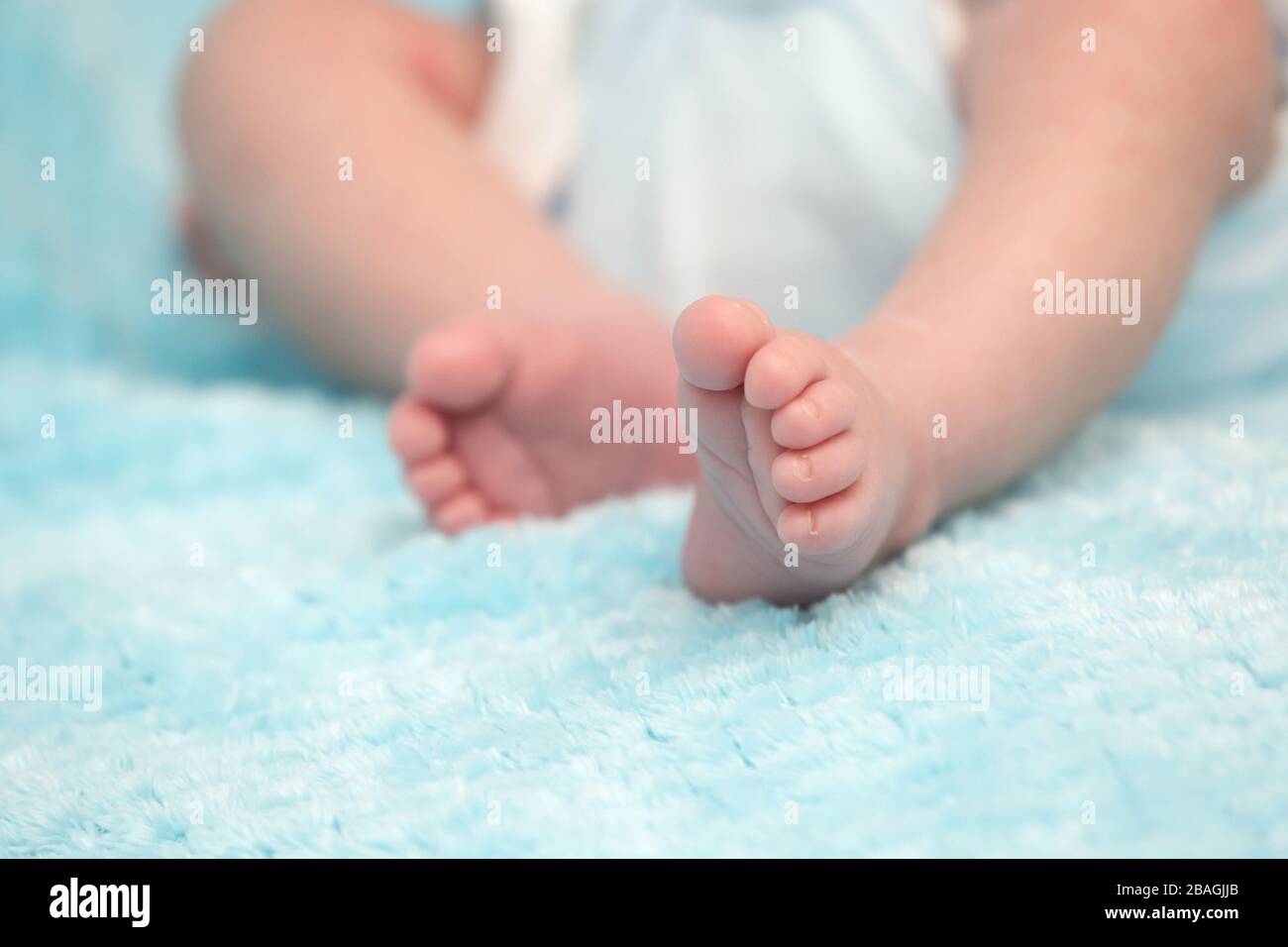 Schmückende kleine Baby-Füße auf weichem blauem Hintergrund Stockfoto