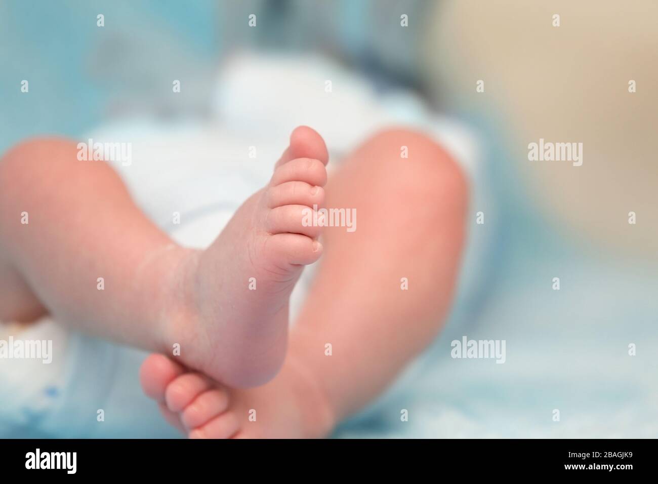 Schmückende kleine Baby-Füße auf weichem blauem Hintergrund Stockfoto