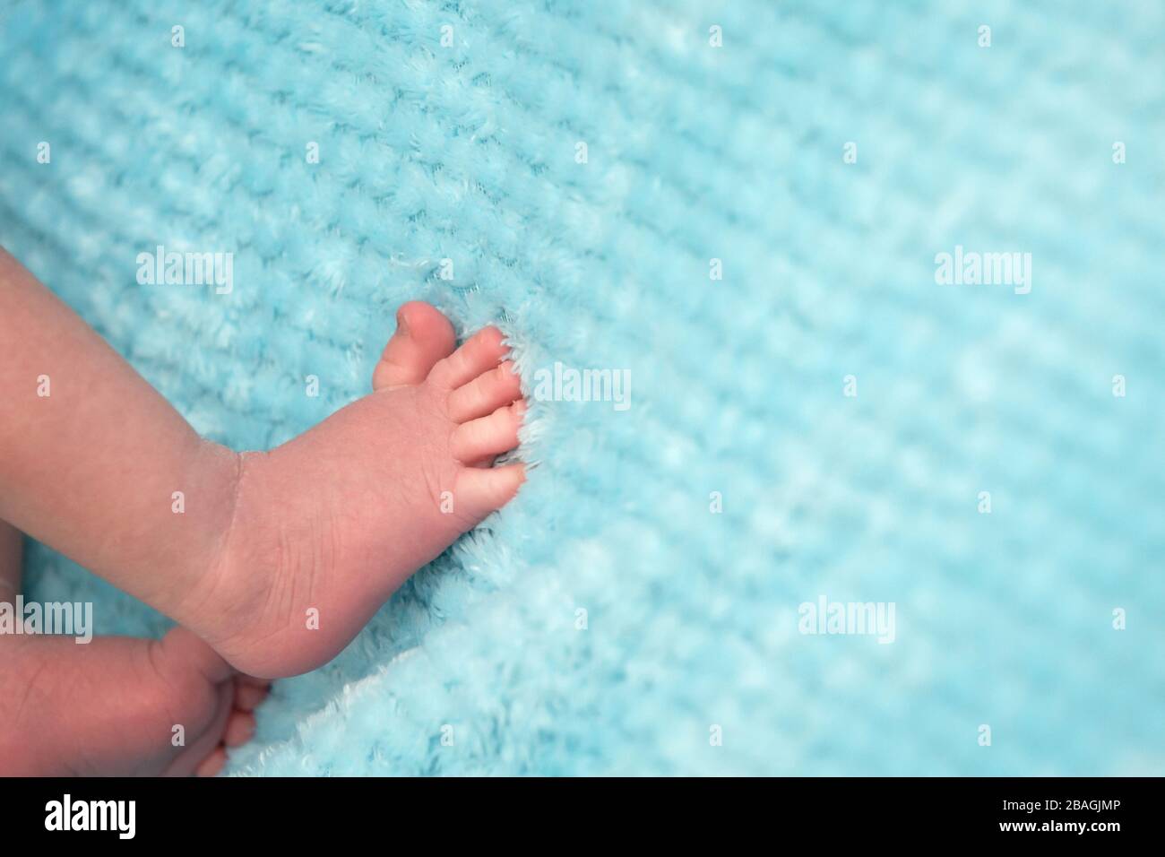 Schmückende kleine Baby-Füße auf weichem blauem Hintergrund Stockfoto