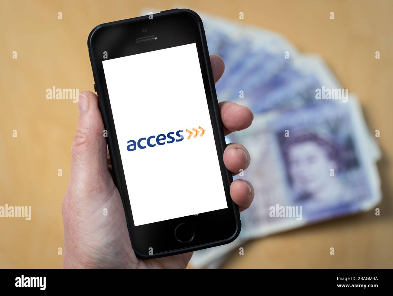 Eine Frau, die das Logo der Access Bank auf einem Mobiltelefon betrachtet. (Nur redaktionelle Verwendung) Stockfoto