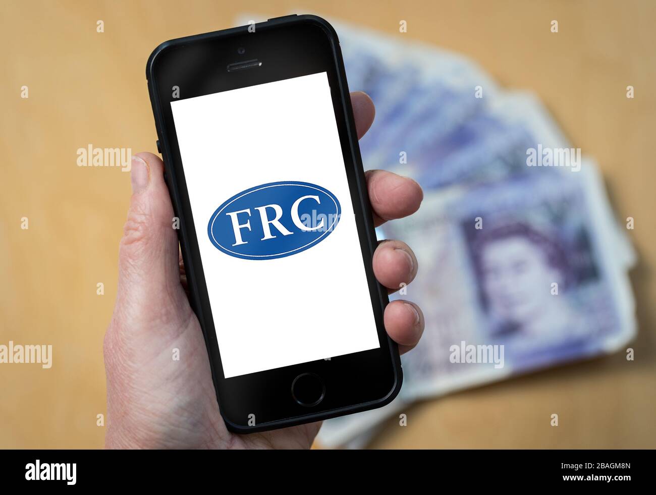 Eine Frau, die das Logo des Financial Reporting Council auf einem Mobiltelefon betrachtet. (Nur redaktionelle Verwendung) Stockfoto