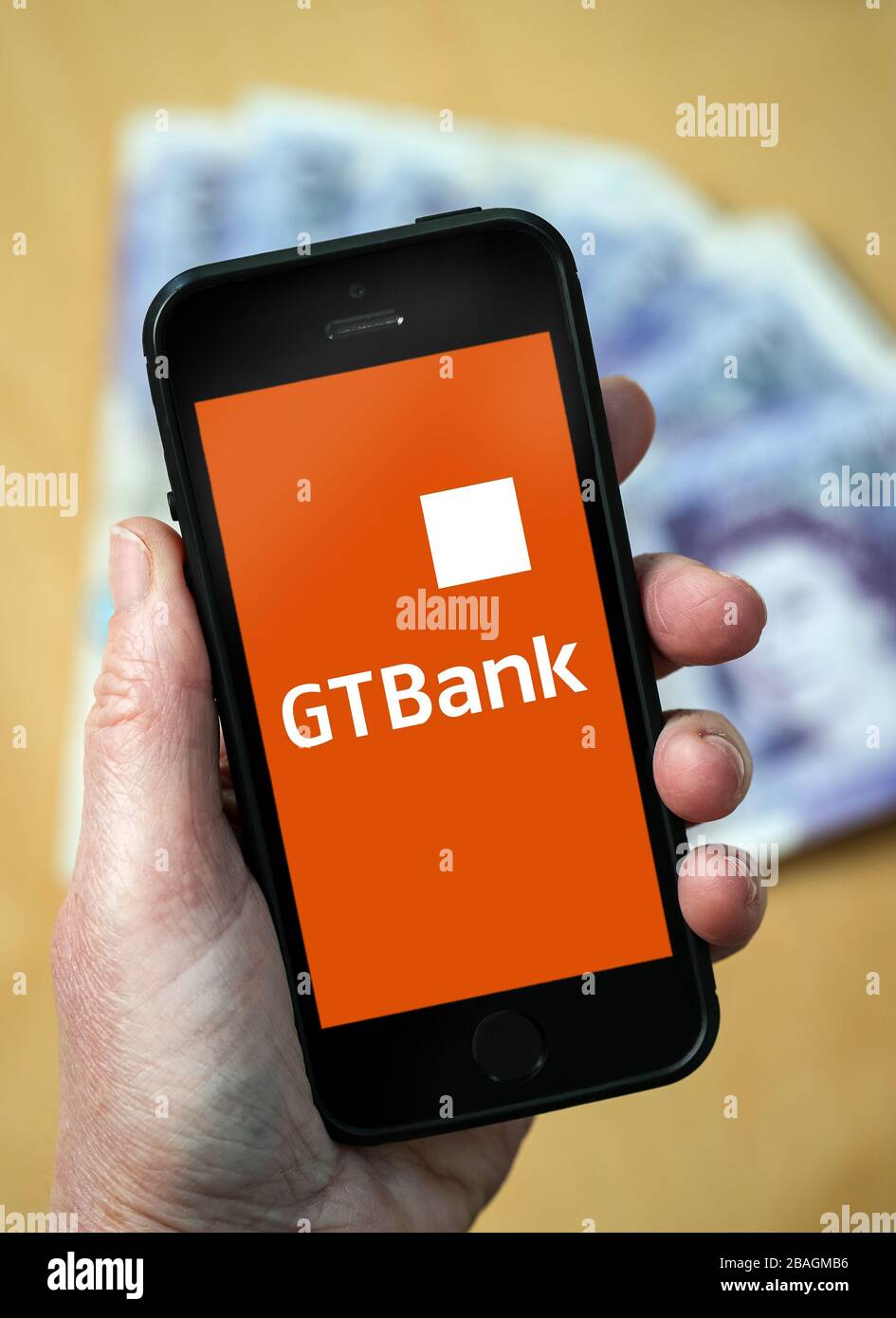 Eine Frau, die das Guaranty Trust Bank-Logo auf einem Mobiltelefon betrachtet. (Nur redaktionelle Verwendung) Stockfoto