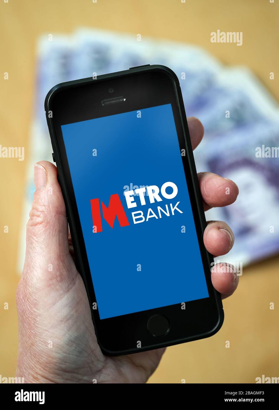 Eine Frau, die das Logo der Metro Bank auf einem Mobiltelefon betrachtet. (Nur redaktionelle Verwendung) Stockfoto