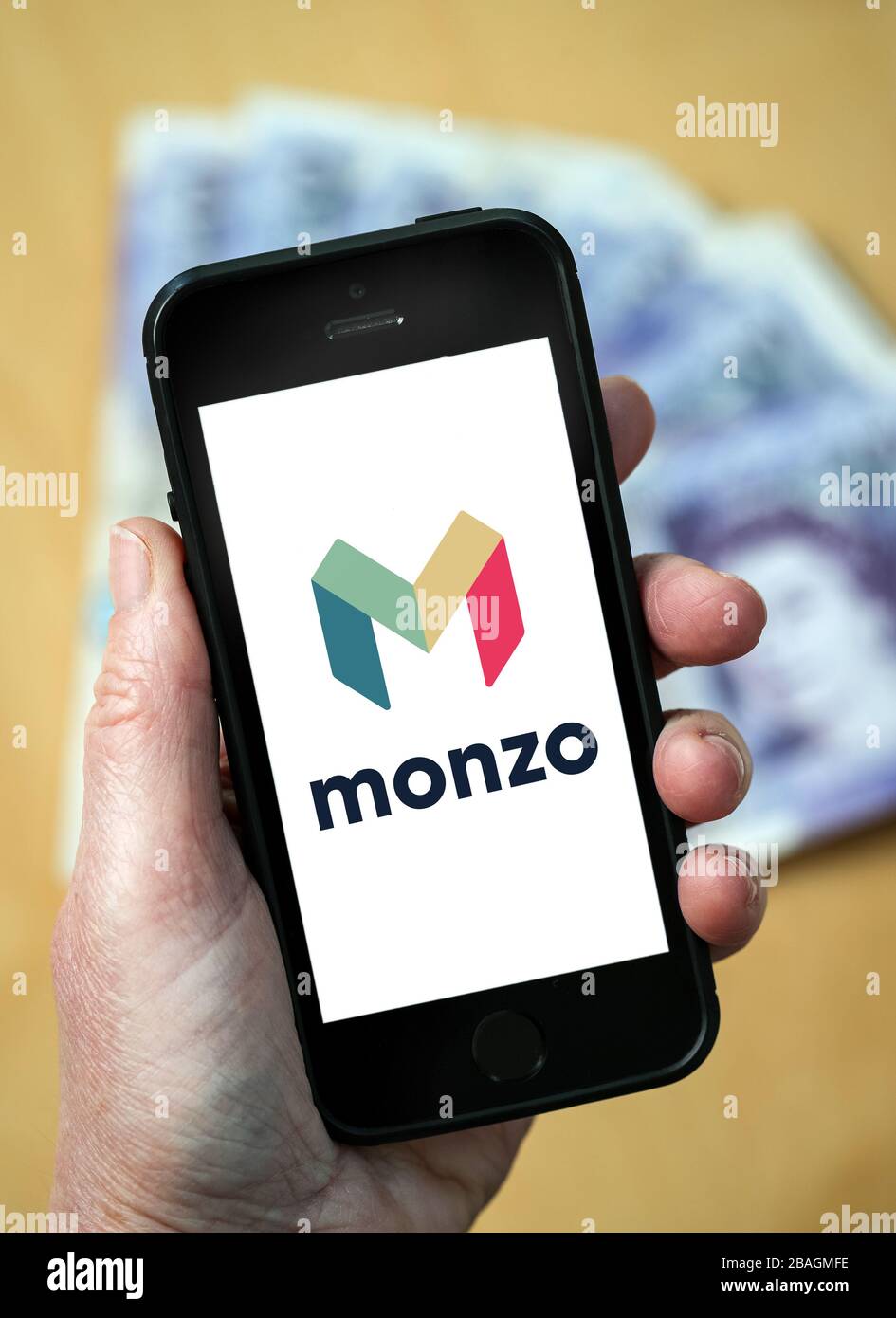 Eine Frau, die das Logo der Monzo Bank auf einem Mobiltelefon betrachtet. (Nur redaktionelle Verwendung) Stockfoto