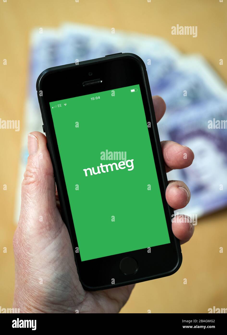 Eine Frau, die das Logo der Online-Investmentverwaltung von Nutmeg auf einem Mobiltelefon betrachtet. (Nur redaktionelle Verwendung) Stockfoto