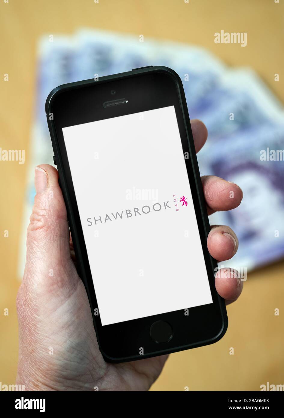 Eine Frau, die das Shawbrook Bank Logo auf einem Handy betrachtet. (Nur redaktionelle Verwendung) Stockfoto
