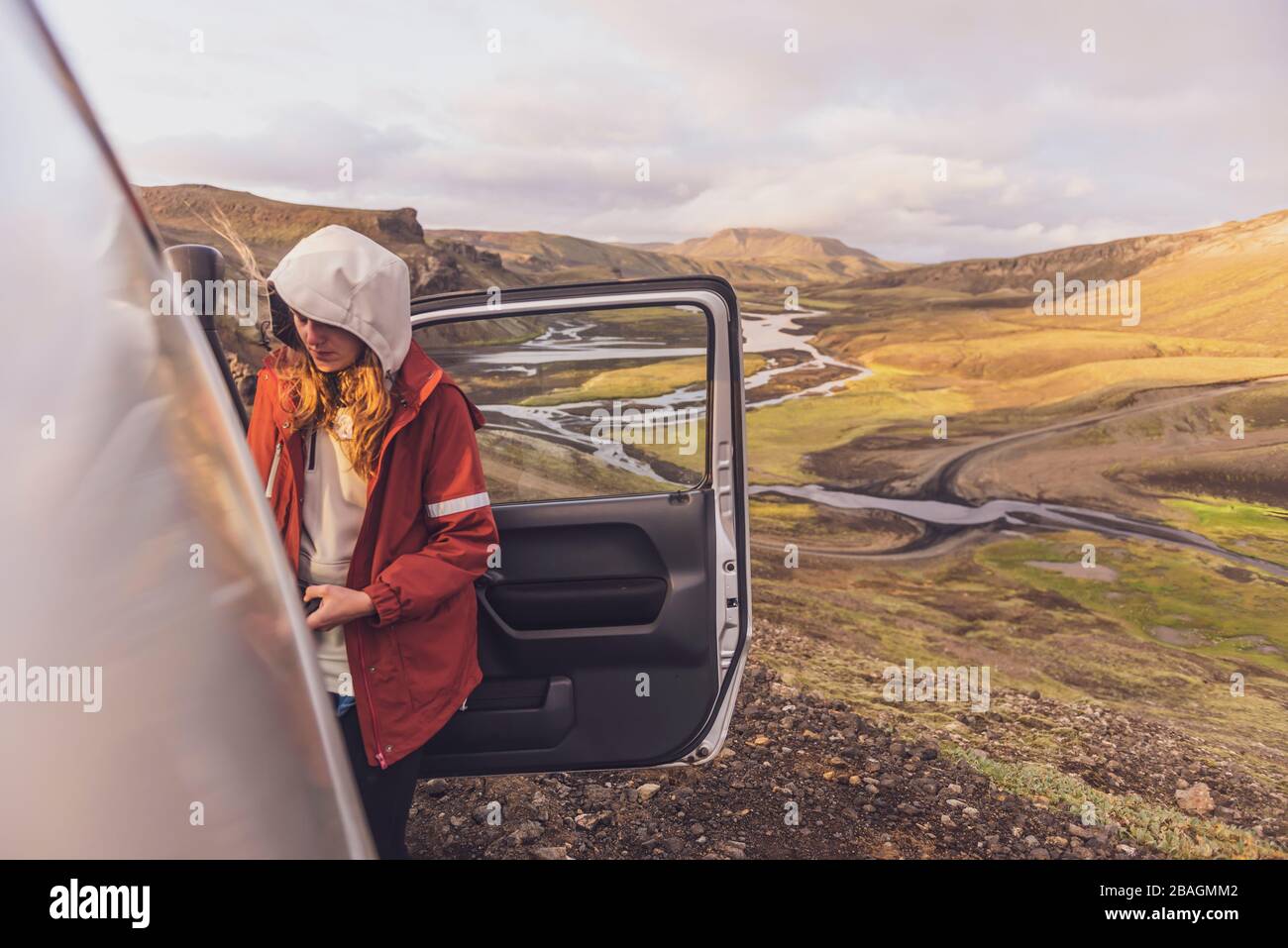 Junge Frau, die vor dem Tal im Hochland Island aus dem Auto fährt Stockfoto