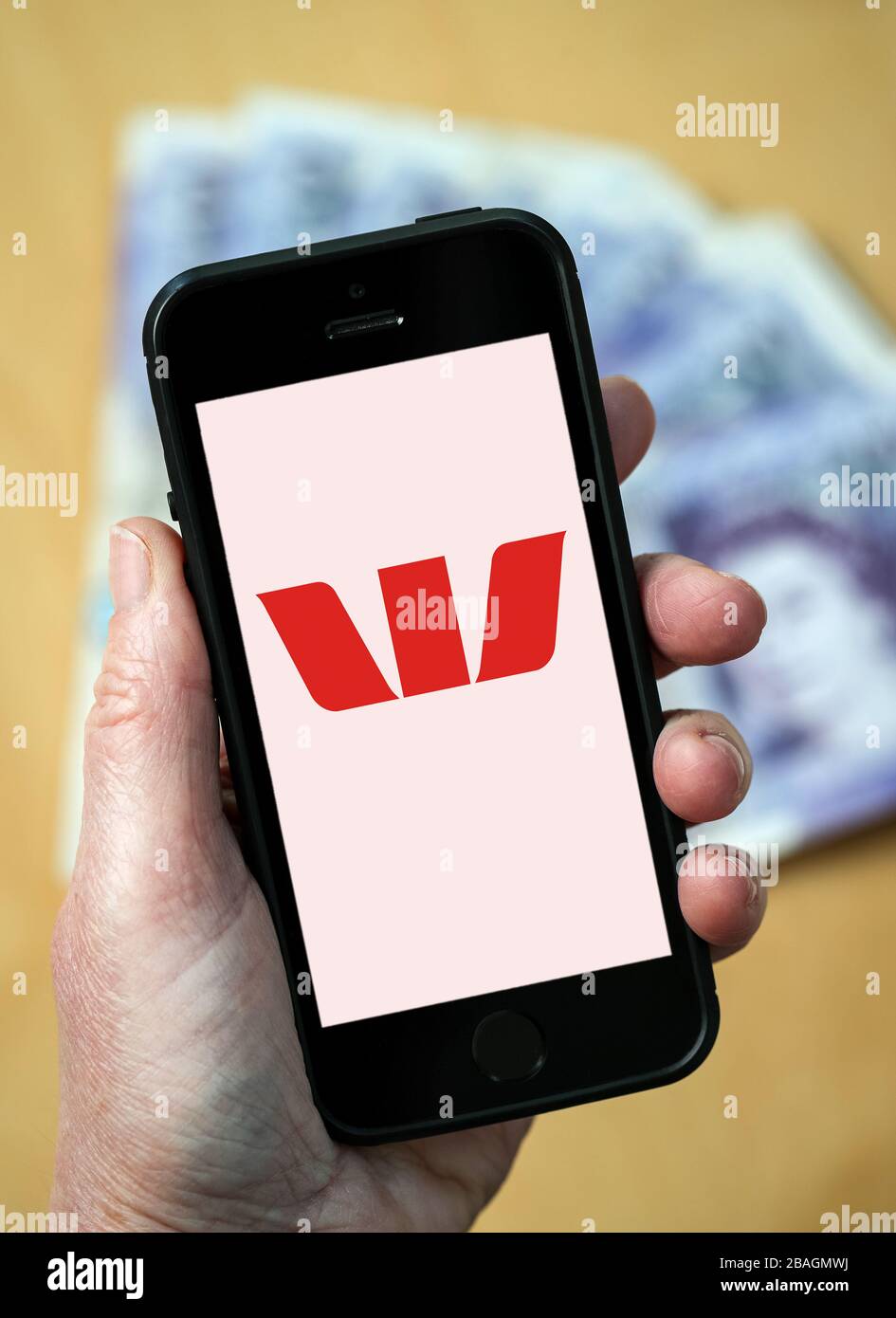 Eine Frau, die das Logo der Westpac Bank auf einem Mobiltelefon betrachtet. (Nur redaktionelle Verwendung) Stockfoto