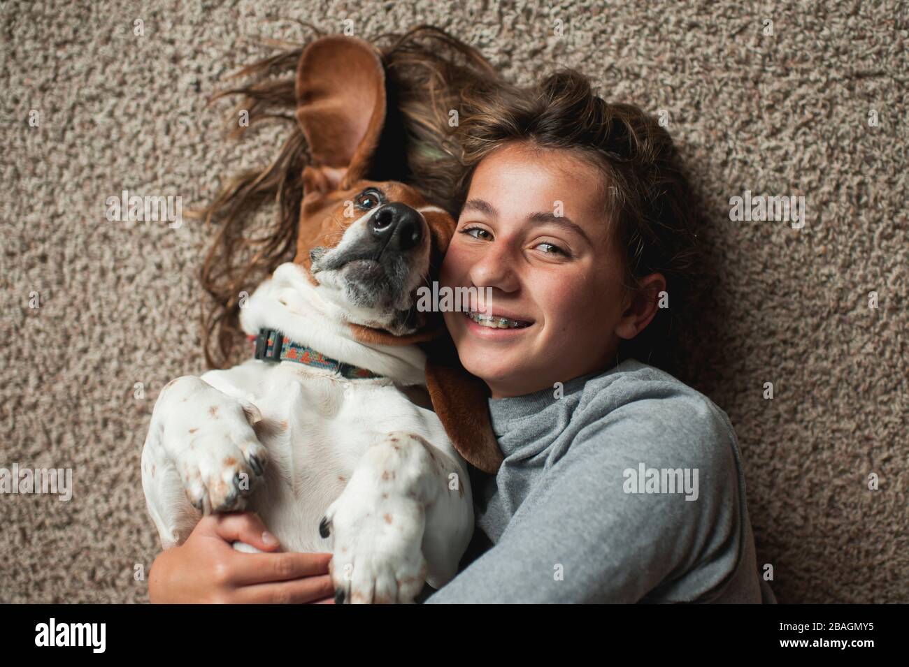 Tween Mädchen posiert mit ihrem Basset Hund während auf dem Teppich liegen Stockfoto