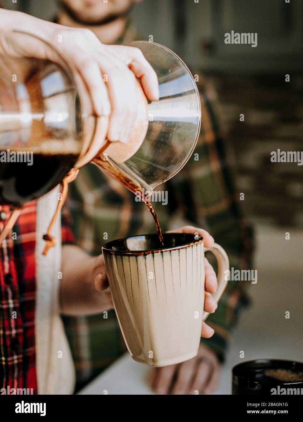 Heißer Kaffee wird aus einem Gießen über in eine braune Kaffeetasse gegossen Stockfoto