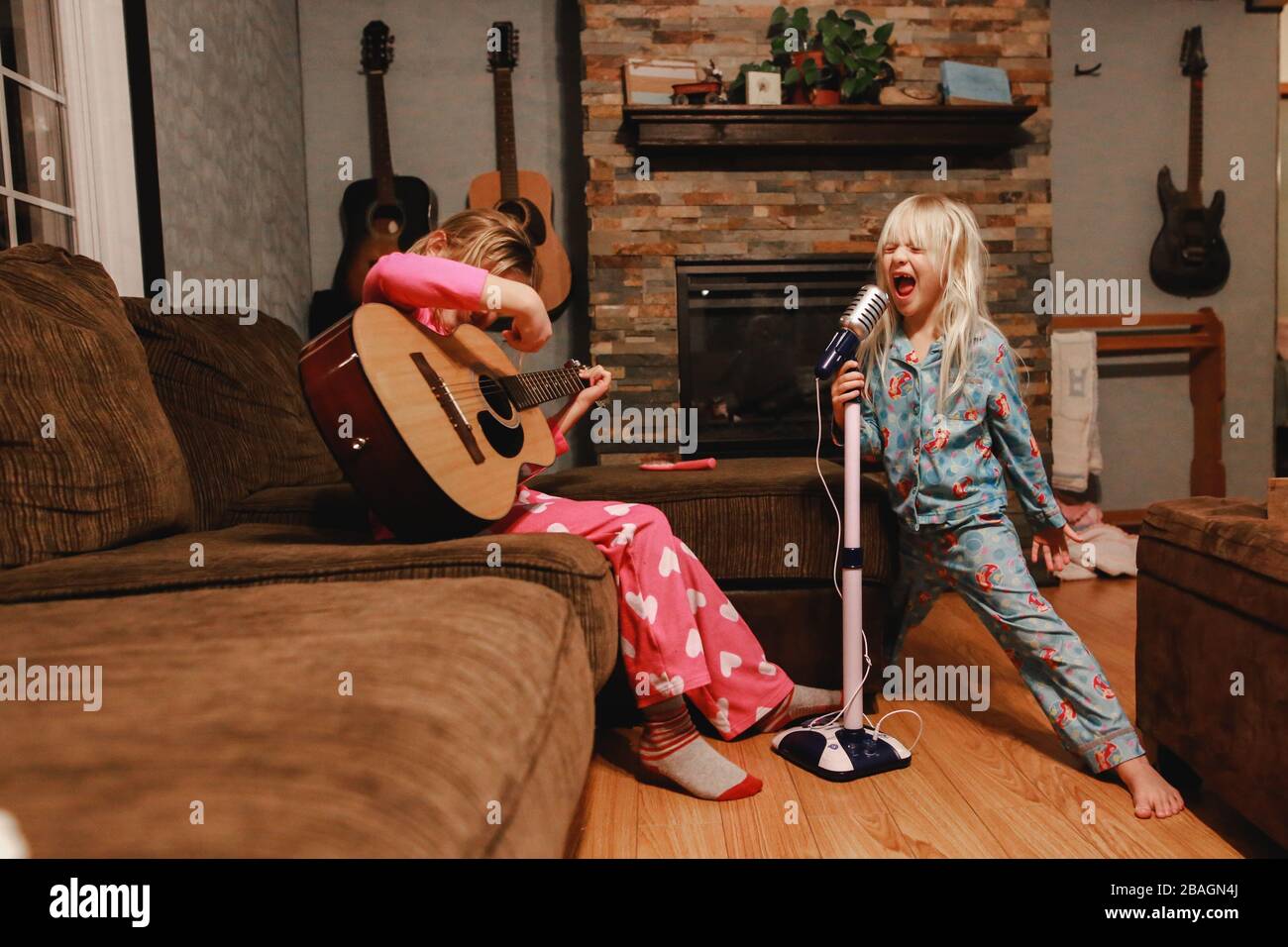 Junge Mädchen singen laut und spielen Gitarre im Wohnzimmer Stockfoto