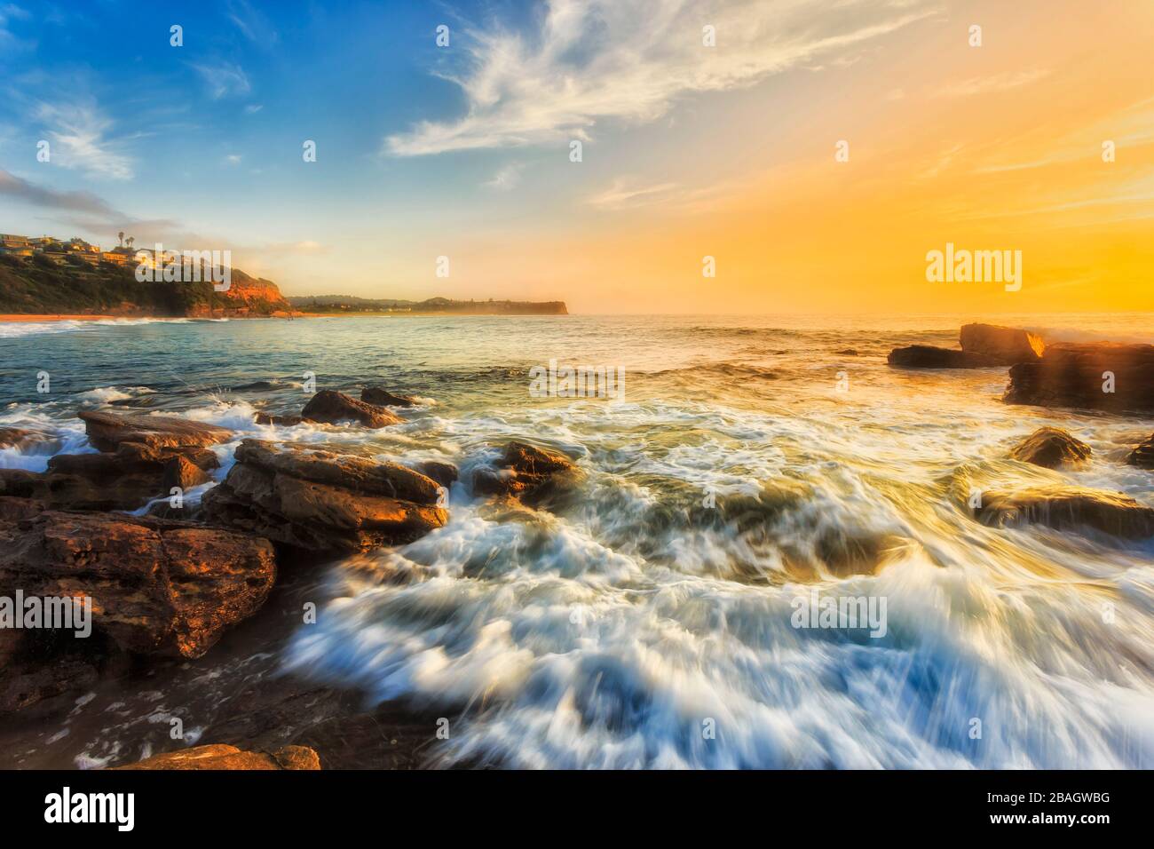 Helles Sonnenlicht über dem Meereshorizont am Warriewood Beach der Nordstrände von Sydney bei Sonnenaufgang. Stockfoto