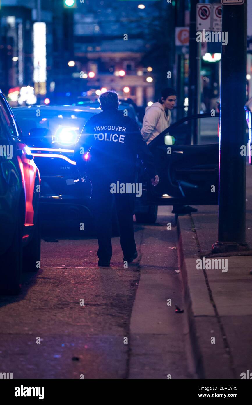 DOWNTOWN VANCOUVER, BC, KANADA - MAR 24, 2020: VPD-Offiziere verhaften einen jungen kaukasischen Täter, der ihn in Handschellen setzt und ihn verarbeitet Stockfoto