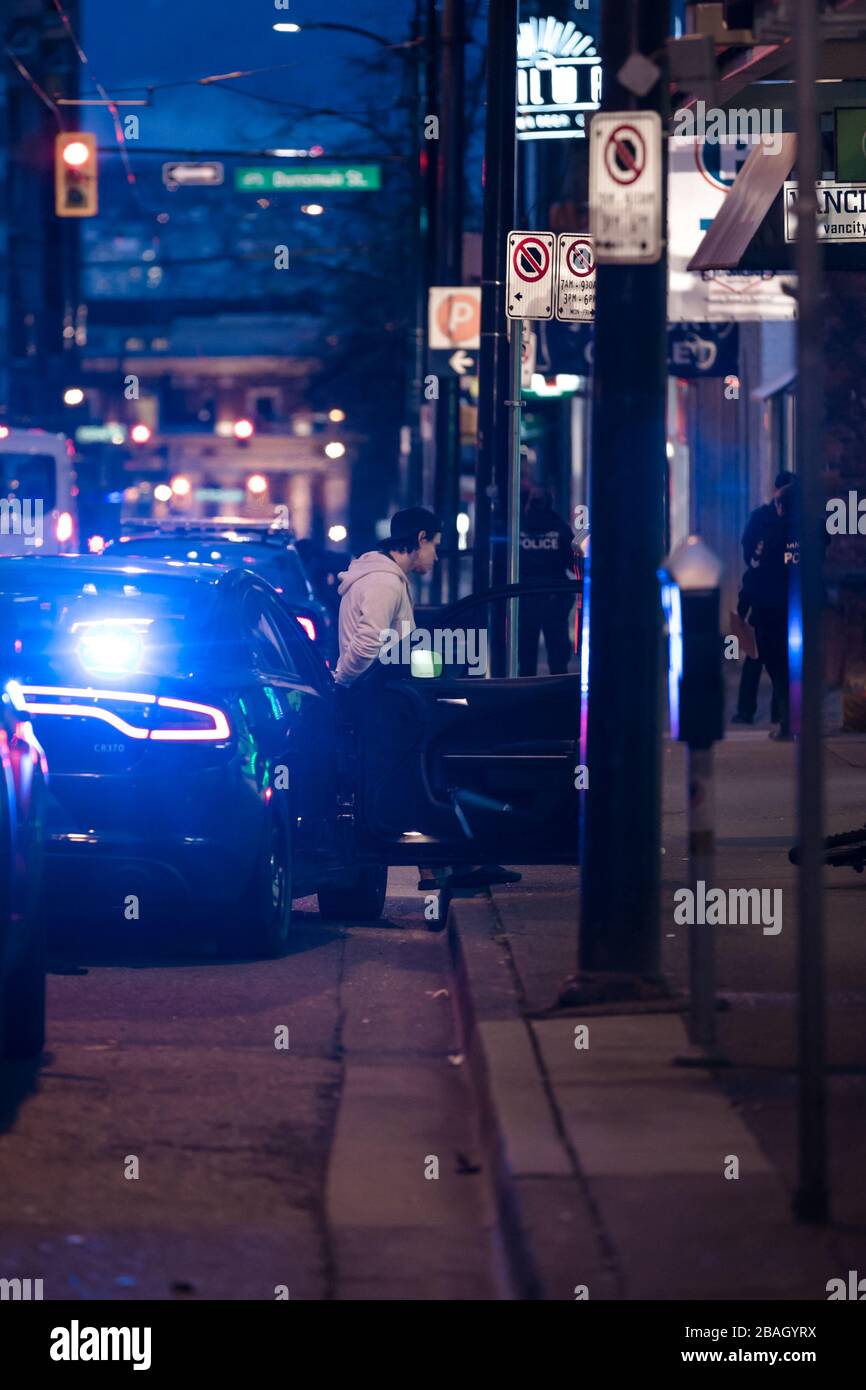 DOWNTOWN VANCOUVER, BC, KANADA - MAR 24, 2020: VPD-Offiziere verhaften einen jungen kaukasischen Täter, der ihn in Handschellen setzt und ihn verarbeitet Stockfoto