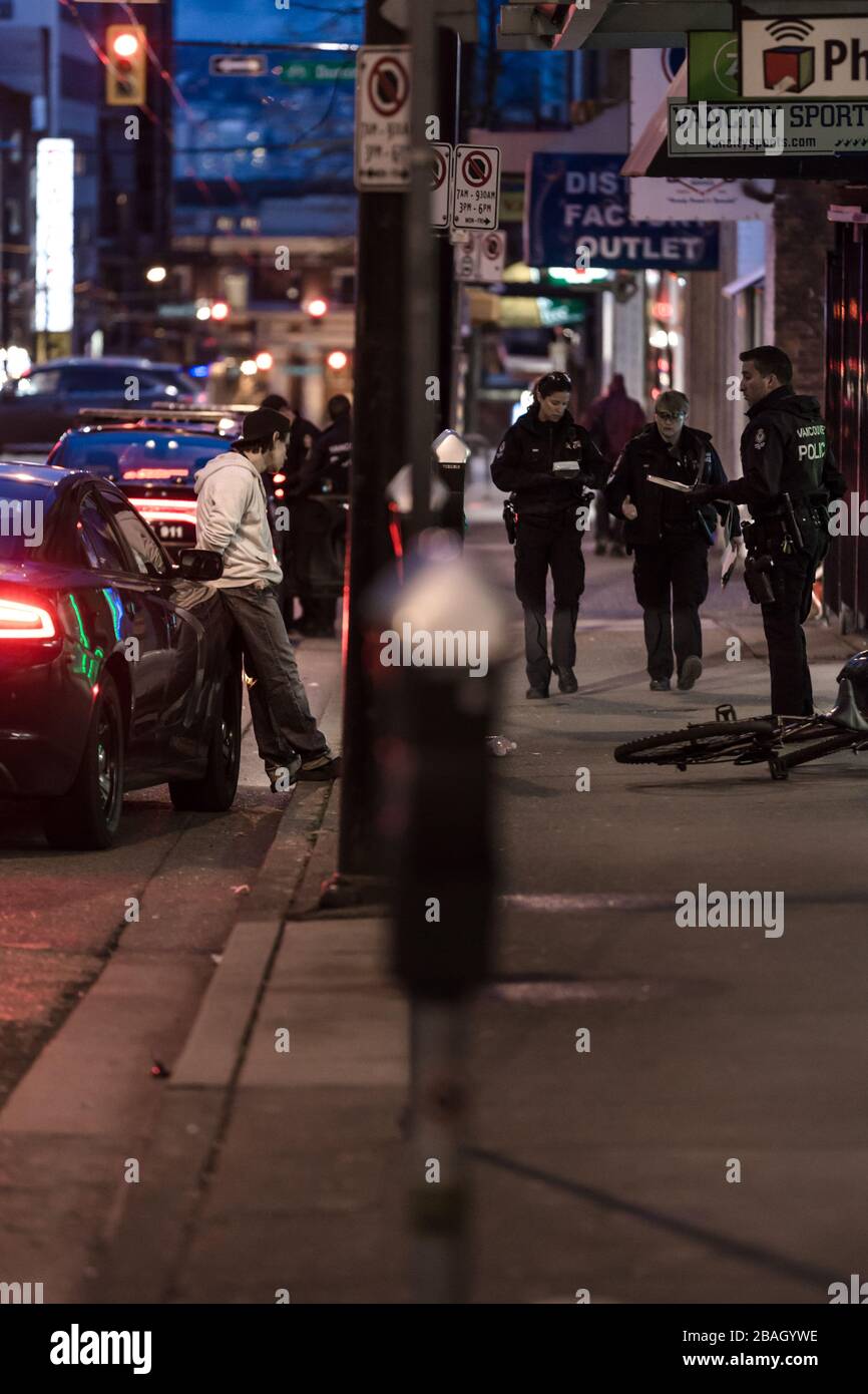 DOWNTOWN VANCOUVER, BC, KANADA - MAR 24, 2020: VPD-Offiziere verhaften einen jungen kaukasischen Täter, der ihn in Handschellen setzt und ihn verarbeitet Stockfoto