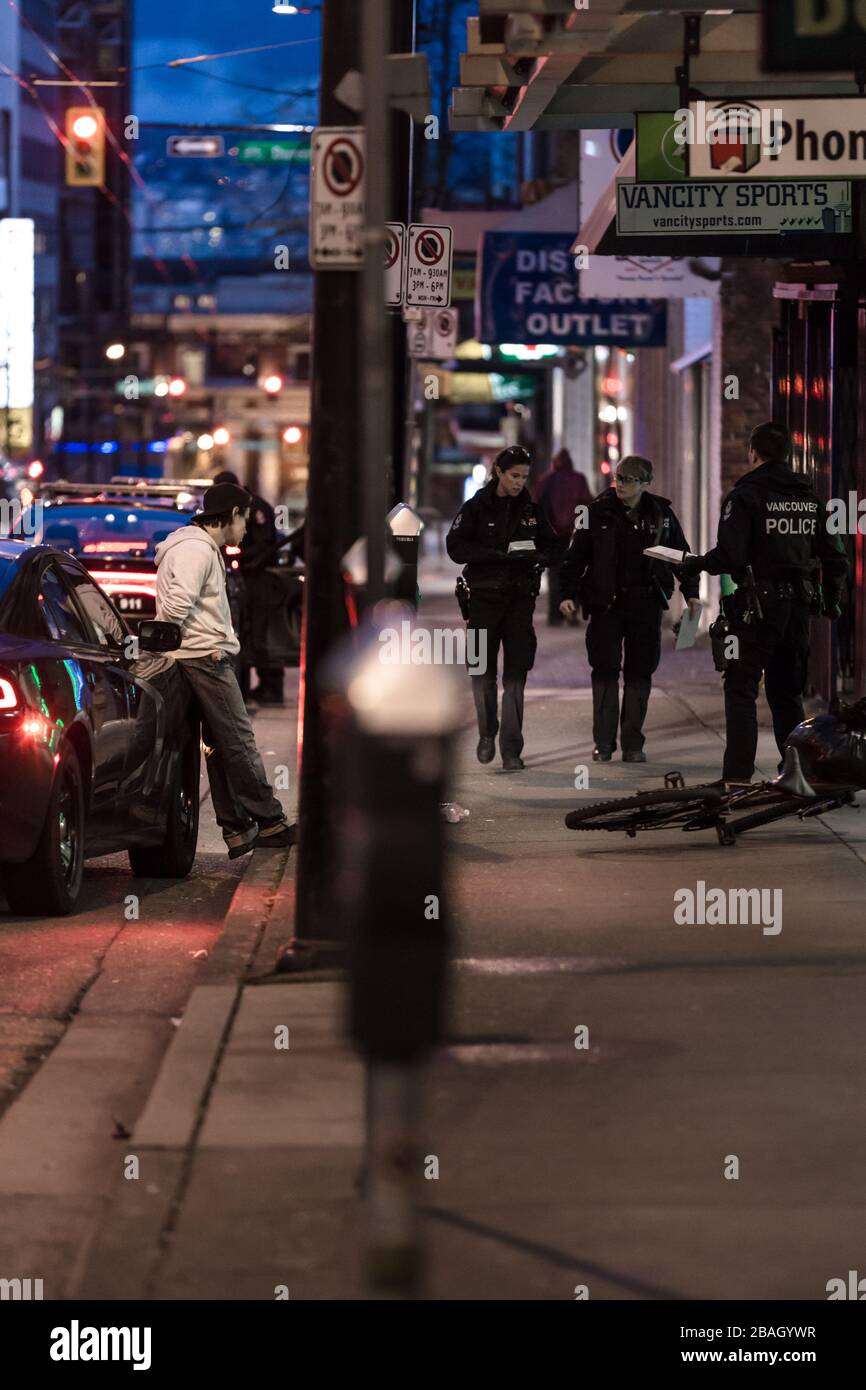 DOWNTOWN VANCOUVER, BC, KANADA - MAR 24, 2020: VPD-Offiziere verhaften einen jungen kaukasischen Täter, der ihn in Handschellen setzt und ihn verarbeitet Stockfoto