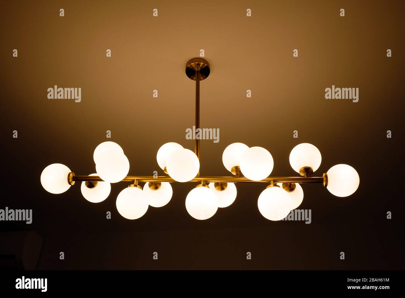 Elektrische Lampen in Form von weißen Kugeln an der Decke. Stilvoller Kronleuchter an der Decke aus Metall und Glas. Stockfoto