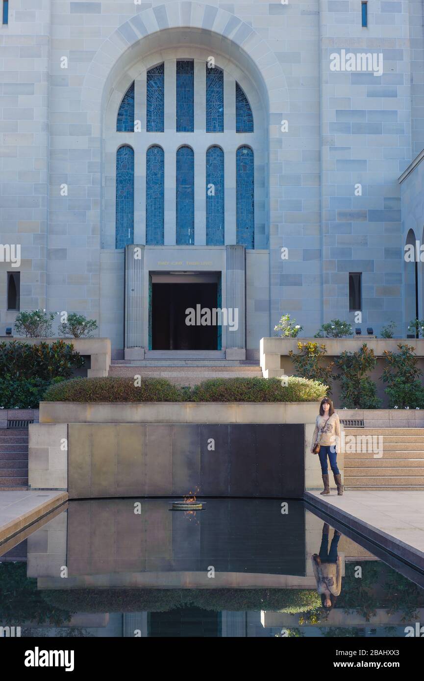 Ein weiblicher Tourist fügt ein Gefühl der Ausmaßung hinzu und steht am Reflexionspool in der Gedächtnishalle mit dem Grab des unbekannten Soldaten im Hintergrund. Stockfoto