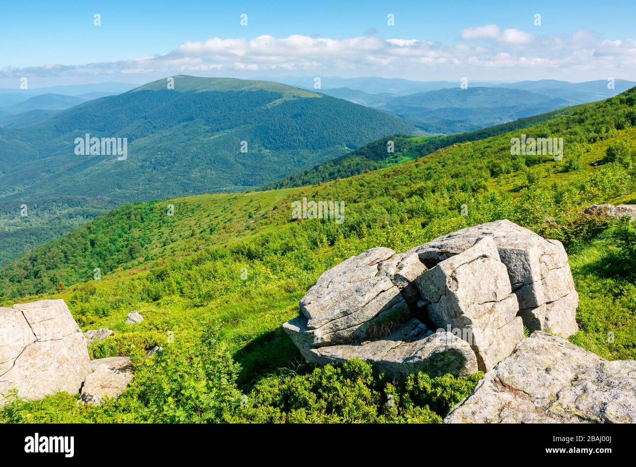 Schöne Sommerlandschaft in den Bergen. Grüne Wiese auf der Hügelseite. Blick in die Ferne unter einem blauen Himmel mit Wolken Stockfoto