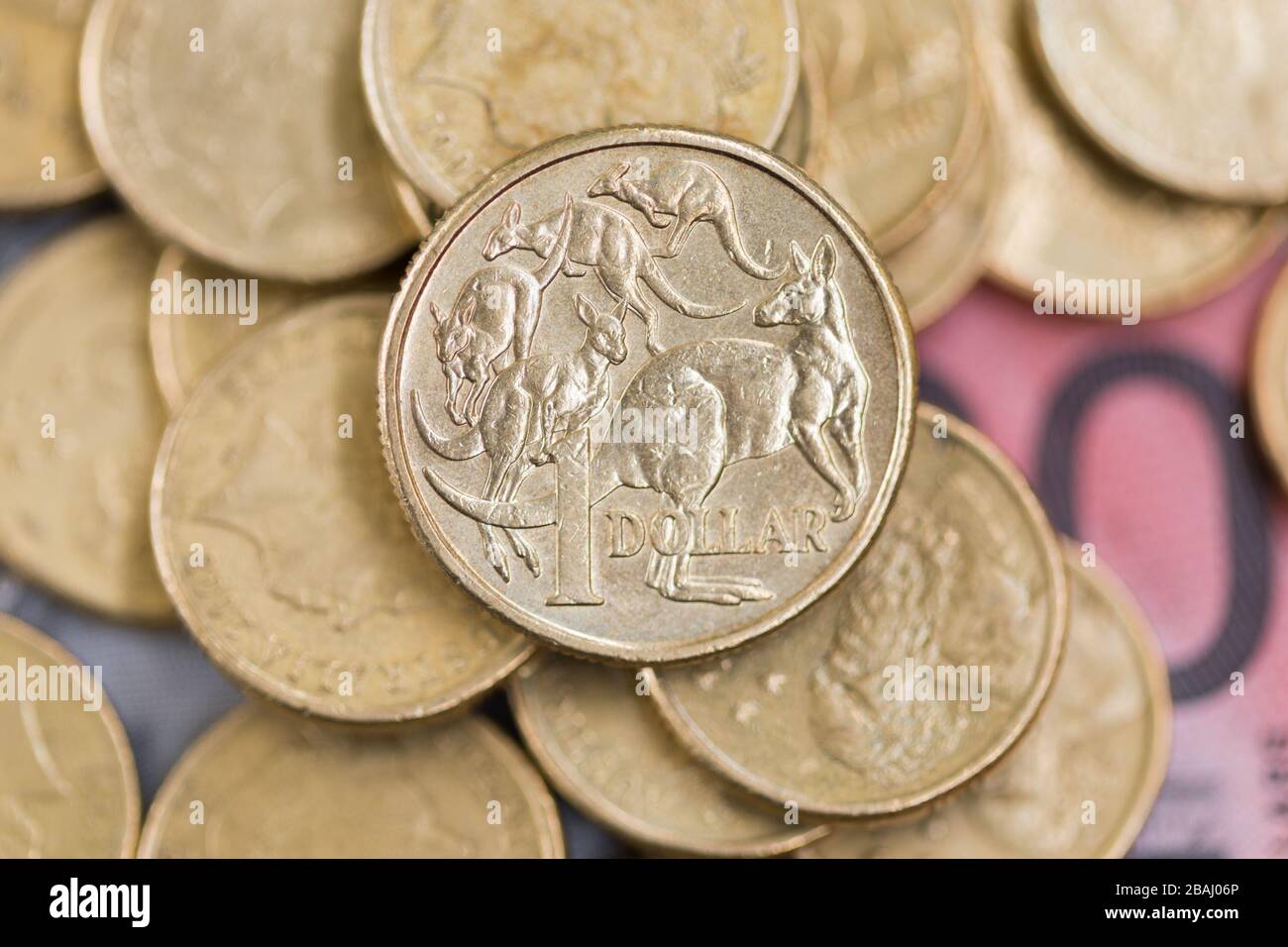 Eine australische Ein-Dollar-Münze, die sich von einem Stapel Münzen und Banknoten abheben kann. Stockfoto