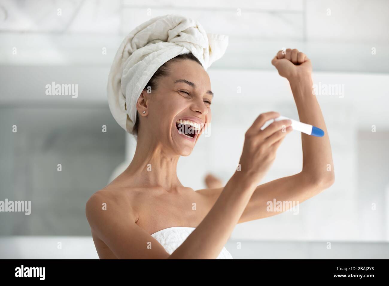 Aufgeregte Frau Anwendung Schwangerschaftstest sehen Sie, dass zwei Streifen glücklich sind Stockfoto