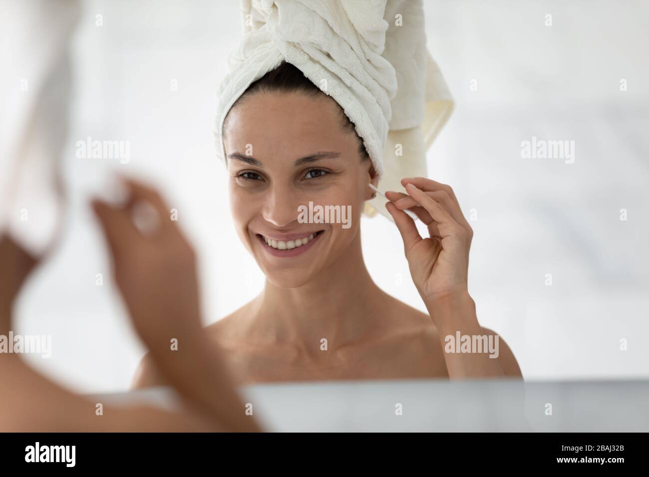 Frau macht morgens Routine, wenn sie Baumwoll-Knospe hält, Ohren reinigt Stockfoto