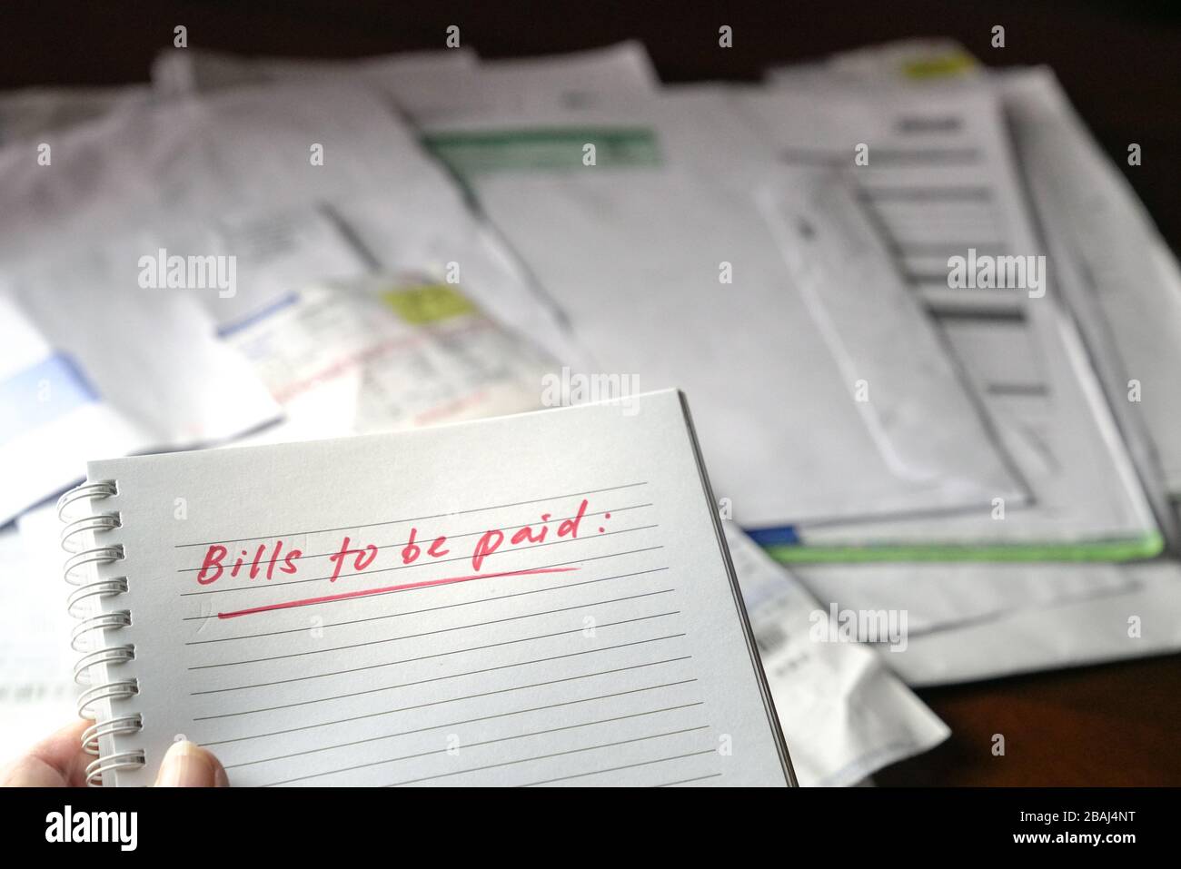Zu zahlende Rechnungen, rot geschriebene Wörter auf Notizbuch mit Rechnungen und Rechnungen im Hintergrund. Konzept der Arbeitslosigkeit oder Rezession. Stockfoto