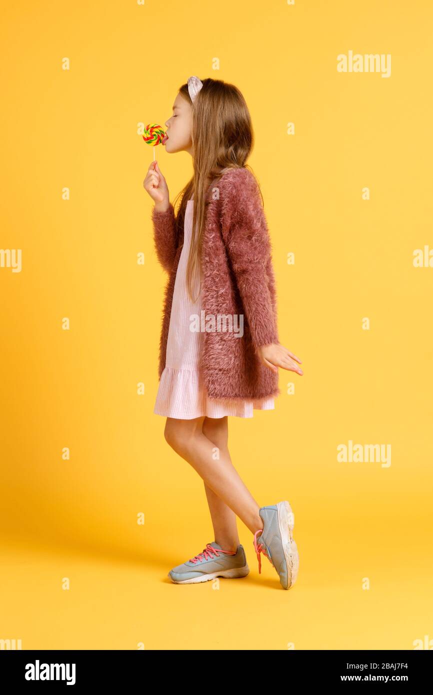 Kleine Mädchen genießen während der Schulpause Lollipops. Glückliche kleine Schüler essen Lollipops. Große wirbelnde Lollipops auf Stöcken Stockfoto