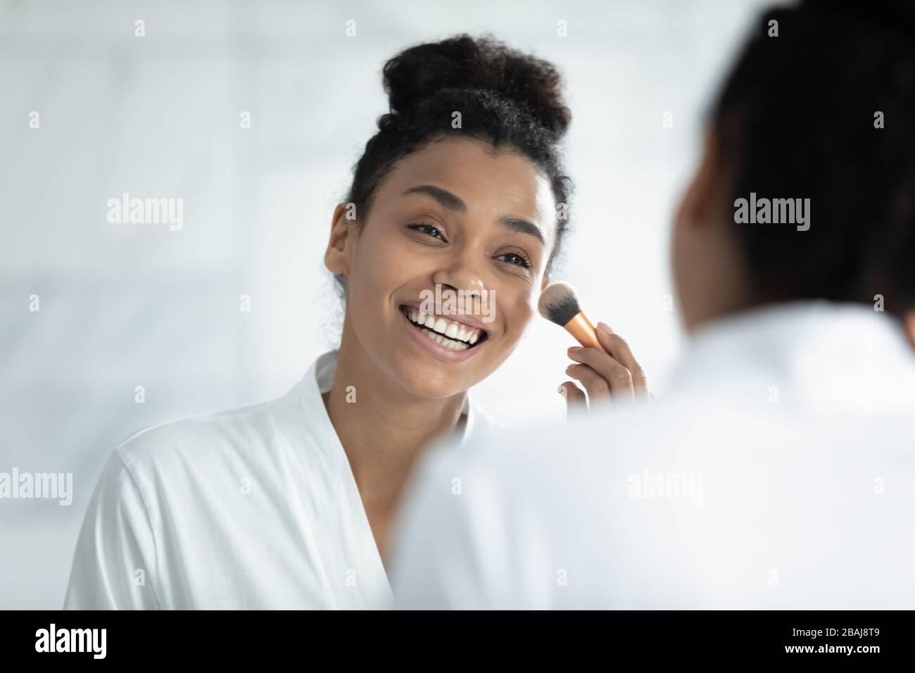 Afrikanische junge Frau hält Bürstenaufbringung Make-up Stockfoto